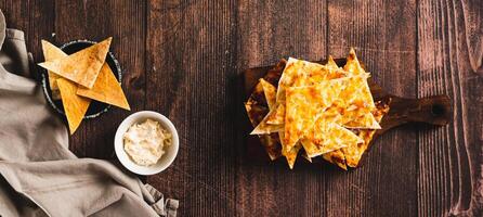 Homemade pita nachos with cheese and garlic on a board on a table top view web banner photo