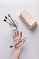 Toothbrush and dental floss in hand against background of toiletries top and vertical view photo