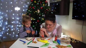 Mom teaches little daughter how to decorate gingerbread with icing video