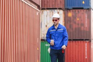 Engineer man walking at shipping yard, Warehouse dock worker work in cargo containers photo