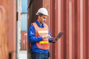 Logistics Professional Inspecting Containers, Engineer Man with Laptop Checking Project in Industry Containers Cargo photo