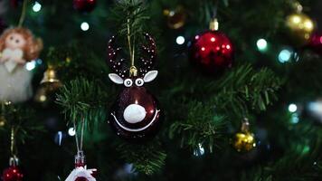 Figurine of a smiling deer hangs on a green branch of a Christmas tree among the balls video