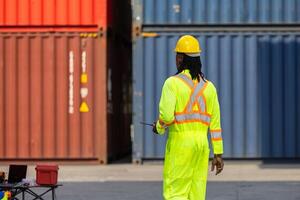 Engineer man walking in industry containers cargo, Foreman dock worker in hard hat at shipping container yard photo