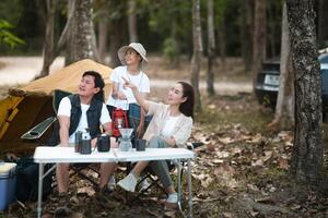The family of three, Mother and father with a son, go camping in the forest. Mother is pointing away photo