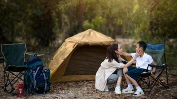 The smiling mother is touching her son face in front of the camping tent. photo