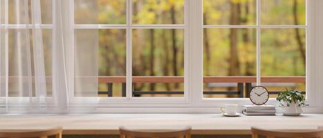 The long wooden table beside large windows and curtain, with the beautiful garden or forest view. photo
