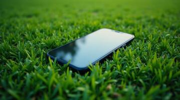 Smartphone lying on green grass outdoors. Lost or forgotten mobile phone on lawn. Concept of technology, communication, and loss photo
