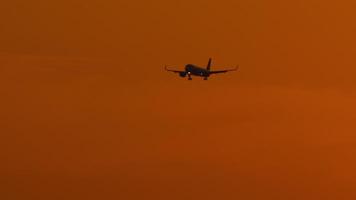 A jet with an unidentifiable livery approach for landing against the backdrop of a golden sunset video