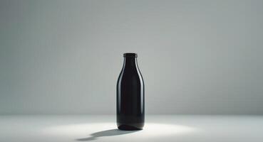 A black bottle sitting on a table with a light shining on it photo