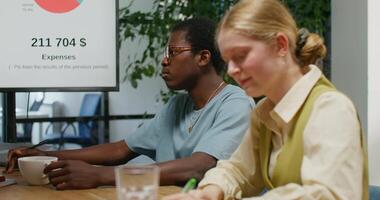 Two people sitting at a table with a laptop and a chart video