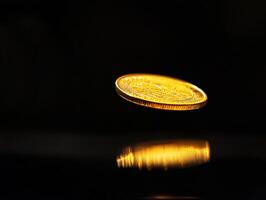 Golden coin flipping in mid-air with reflections on surface photo