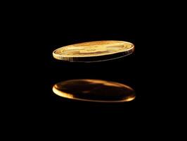 Golden coin spinning in mid-air with reflection on surface photo