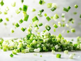 Chopped green onions falling on a white surface in bright light photo