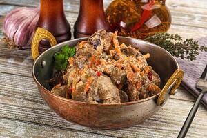 A bowl of meat and vegetables on a table photo