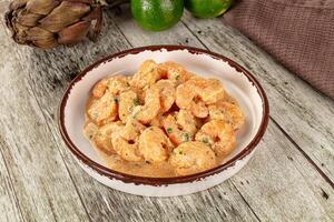 A bowl of shrimp and a lime on a wooden table photo