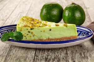 A piece of cheesecake on a plate with two limes photo