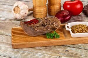 A wooden cutting board with meat, spices and vegetables photo