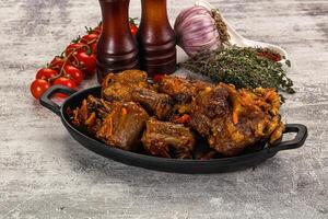 A black dish with meat and vegetables on a table photo