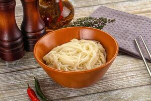 A bowl of noodles with chopsticks and spices photo