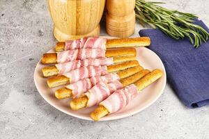 A plate topped with bacon wrapped bread sticks photo