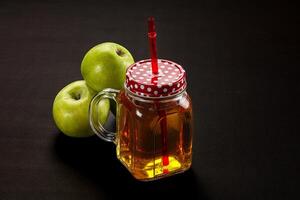 A jar of apple juice with a red straw photo