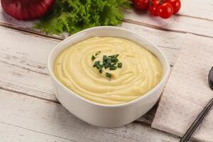 A bowl of creamy mashed potatoes with a fork and a knife photo