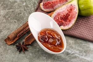 A bowl of fig jam and some spices on a table photo