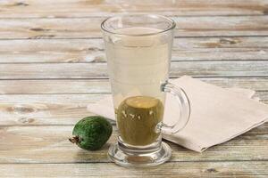A glass of water and a green fruit on a table photo