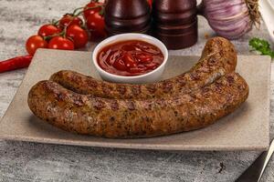 Two sausages on a plate with ketchup and tomatoes photo