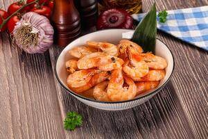 A bowl of shrimp with garlic and herbs on a wooden table photo