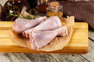 A wooden cutting board with chicken legs and spices photo