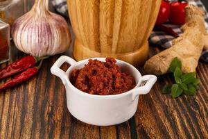 A bowl of chili sauce next to a bottle of garlic paste photo