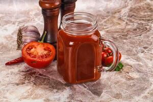 A jar of tomato sauce next to a pepper and a garlic clove photo