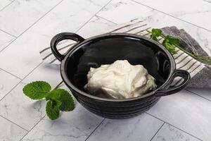 A bowl of cream sitting on a table with a towel photo