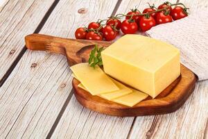 Cheese on a wooden cutting board with tomatoes photo