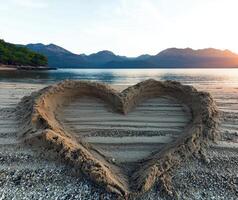 Sand heart on a beach at sunset photo