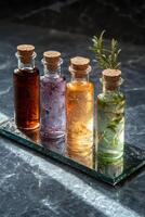Four glass bottles with cork stoppers filled with different liquids and herbs on a reflective surface photo