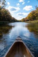 Canoeing on a river in autumn with colorful trees and a blue sky photo