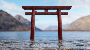 A red torii gate stands in calm water with mountains in the background photo