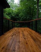 A wooden deck with a railing overlooks a lush green forest photo