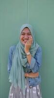A woman wearing a hijab is laughing photo