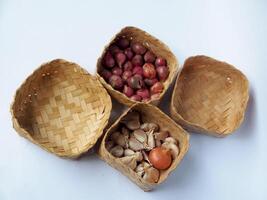 Wicker baskets containing garlic and shallots are artistically displayed with an on a white surface, showcasing rustic kitchen elements and traditional food presentation for culinary themes. photo