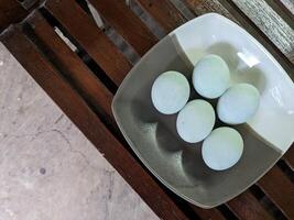 A beautiful arrangement of salted duck eggs on a plate, artistically placed in a grey ceramic dish on a rustic wooden surface, captures the essence of natural and simple cuisine. photo