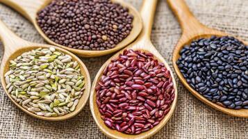 Colorful Seeds and Grains in Wooden Spoons on Burlap photo