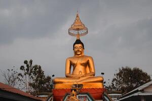 Majestic Golden Buddha Statue Situated Beneath a Dramatic Cloudy Sky Displaying Beauty photo