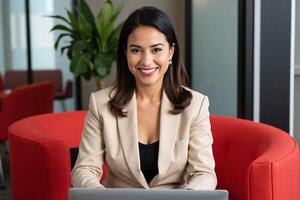 A woman in a business suit sitting at a table with a laptop photo