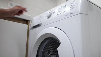 Female hands loads dirty laundry into the washing machine and sets the wash cycle. Concept of caring for cleanliness and comfort at home, simplifying daily life with modern technology video