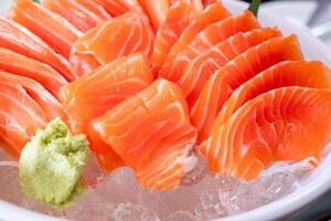 Raw salmon slice or salmon sashimi and wasabi in Japanese style fresh serve on ice in white bowl. Japanese traditional food or with low calories and high photo