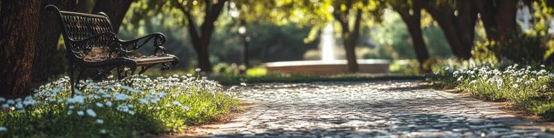 Tranquil pathway in a sunlit park with bench and blooming flowers photo