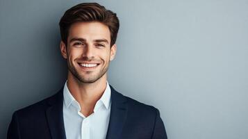 Smiling young man in formal attire against gray background for professional portrait concept photo